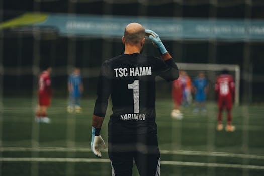 A soccer goalkeeper stands ready for a penalty kick on a field.