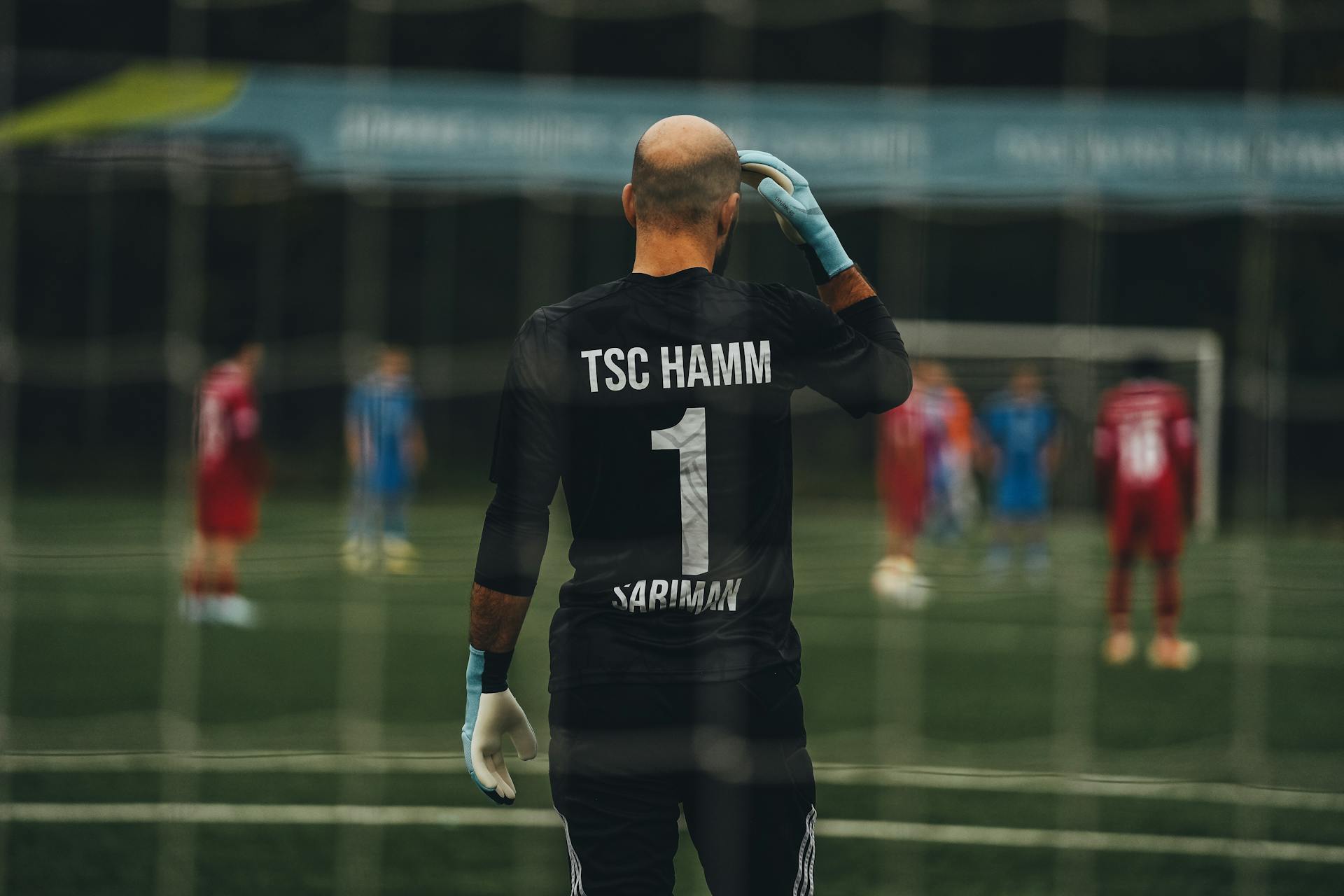 A soccer goalkeeper stands ready for a penalty kick on a field.