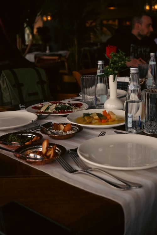 Free Elegant dining table setting with a variety of appetizers and a rose centerpiece, creating a cozy atmosphere. Stock Photo