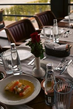 A sophisticated dining setup with decorative flower centerpiece and elegant tableware.