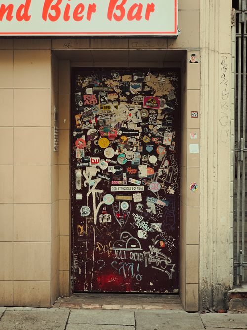 Free A sticker-covered door at a bar entrance in Berlin showcasing urban street art. Stock Photo