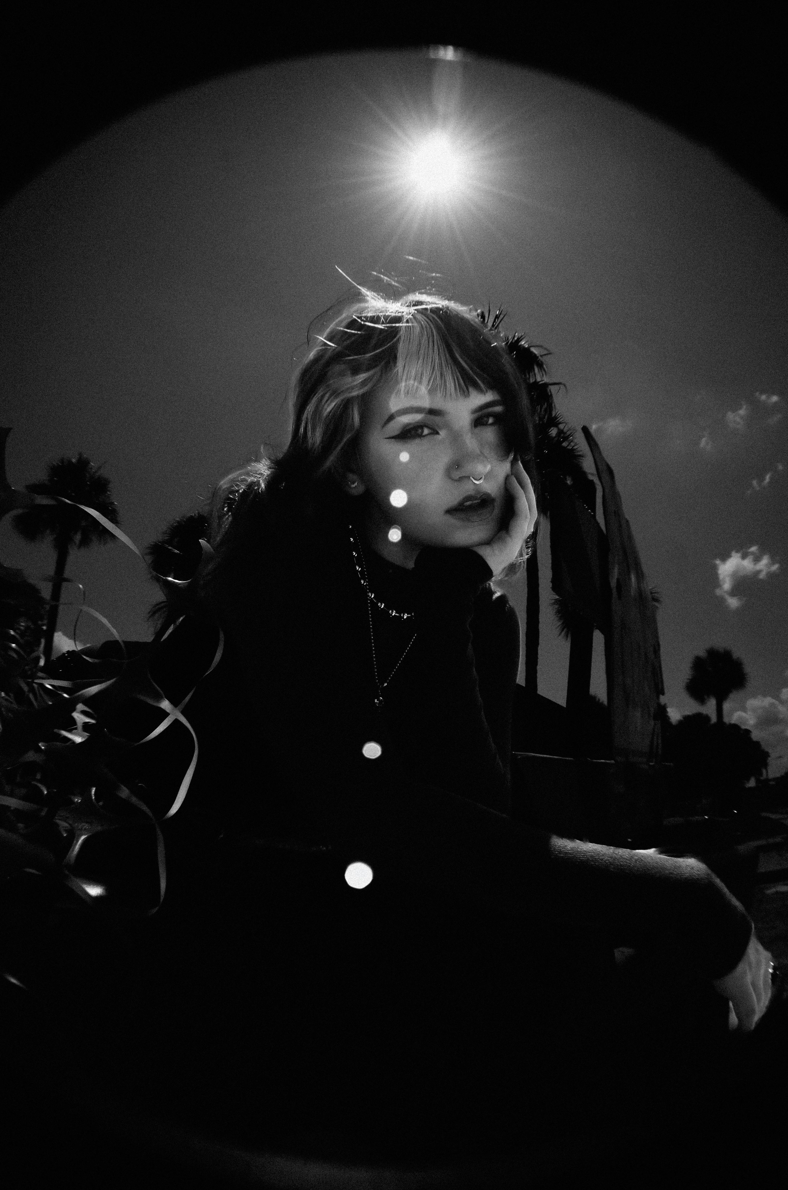Artistic black and white portrait capturing moody expression under a bright sun.
