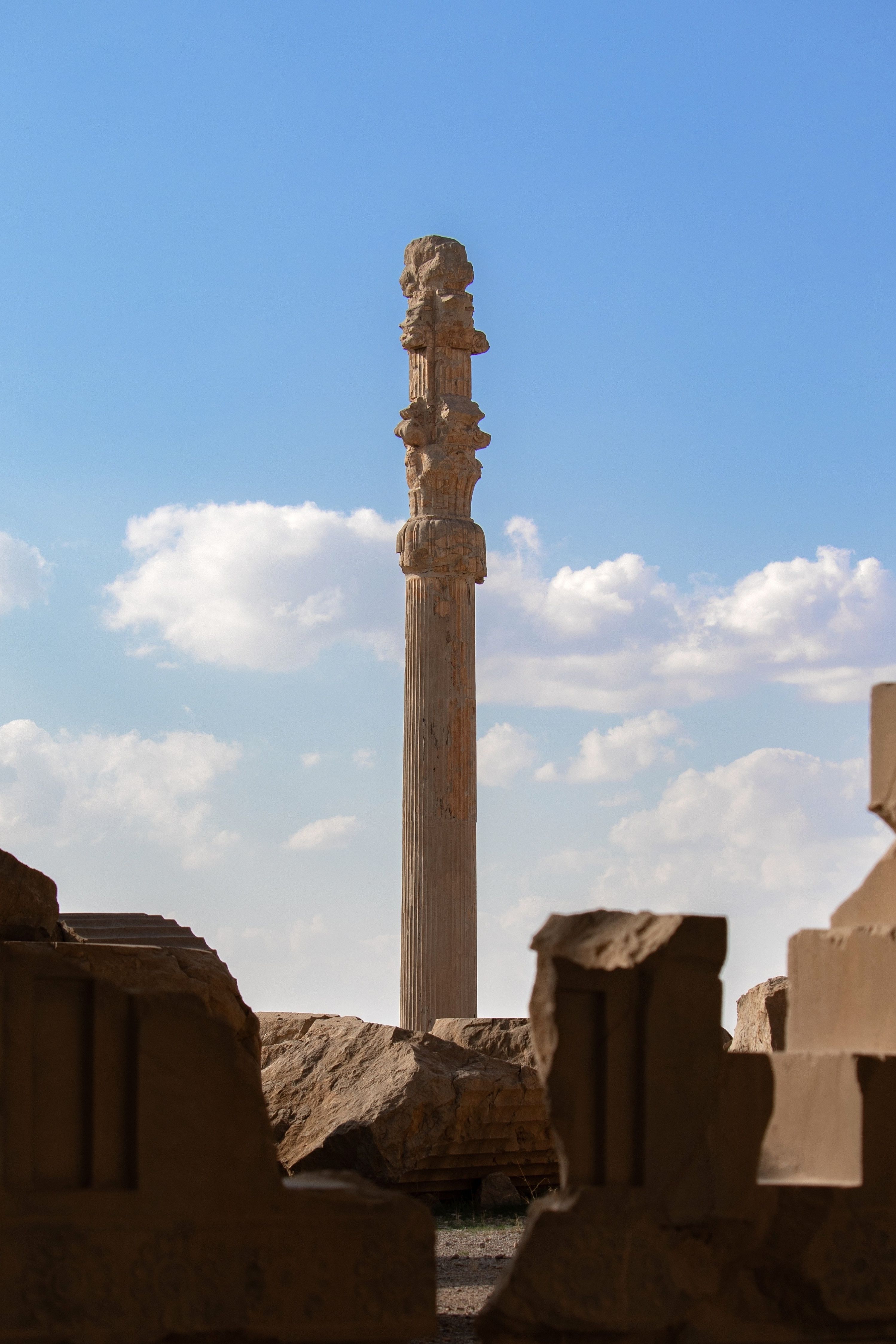 Historic column at Persepolis in Marvdasht, Iran against a clear blue sky.