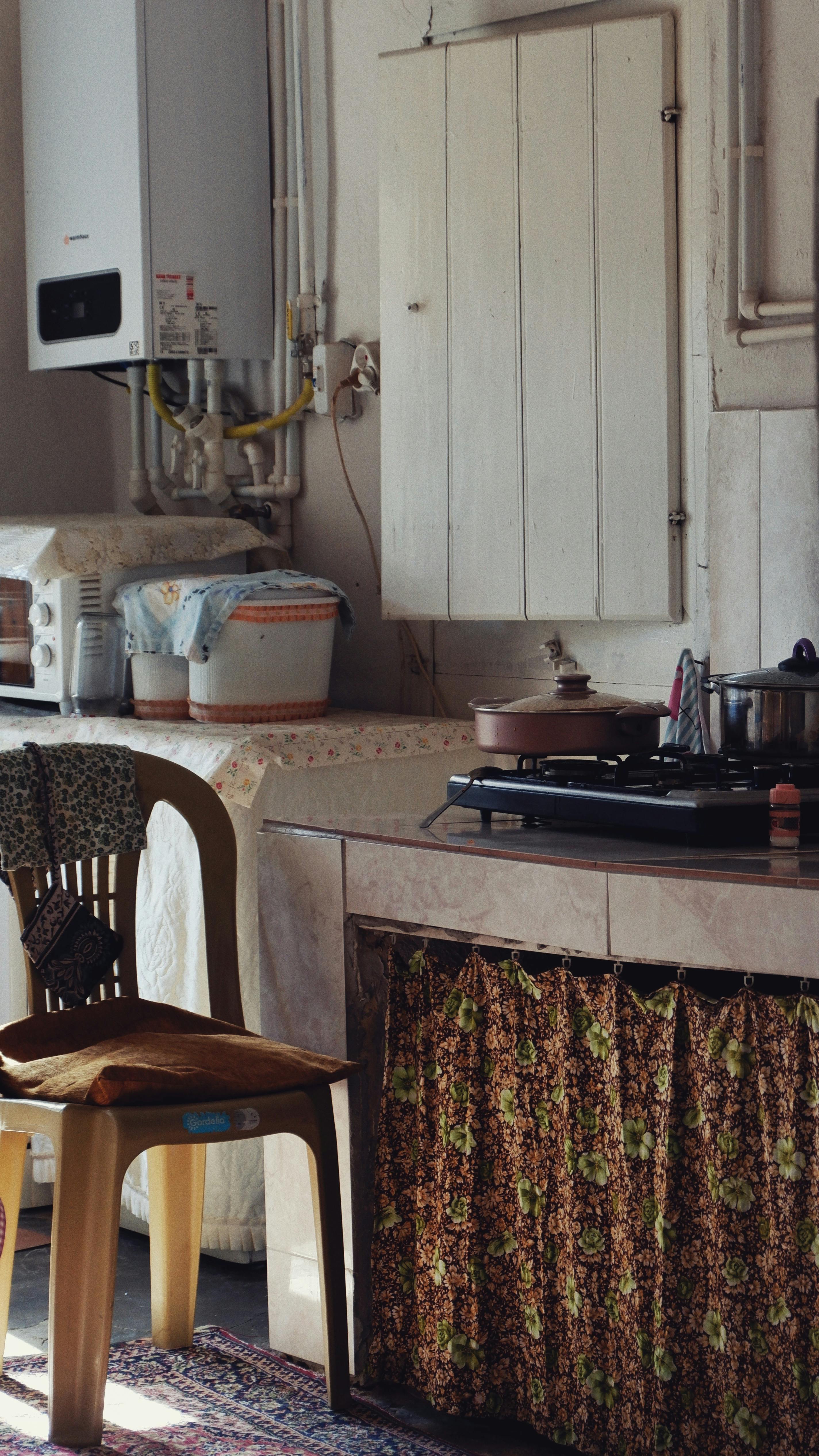A cozy vintage-style kitchen with gas stove, wooden chair, and warm decor.