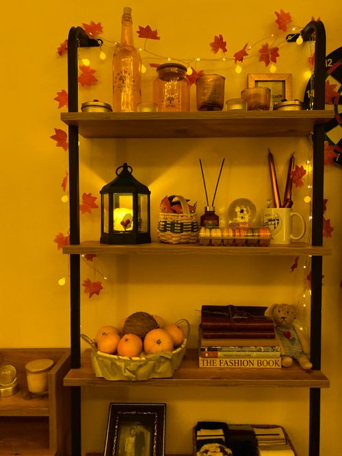 Free A cozy shelf decorated with autumn leaves, books, and warm lighting. Stock Photo