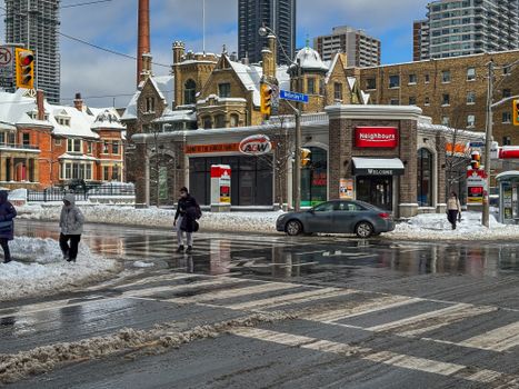 Winter view of a snowy intersection in downtown Toronto, capturing historic architecture and urban life.