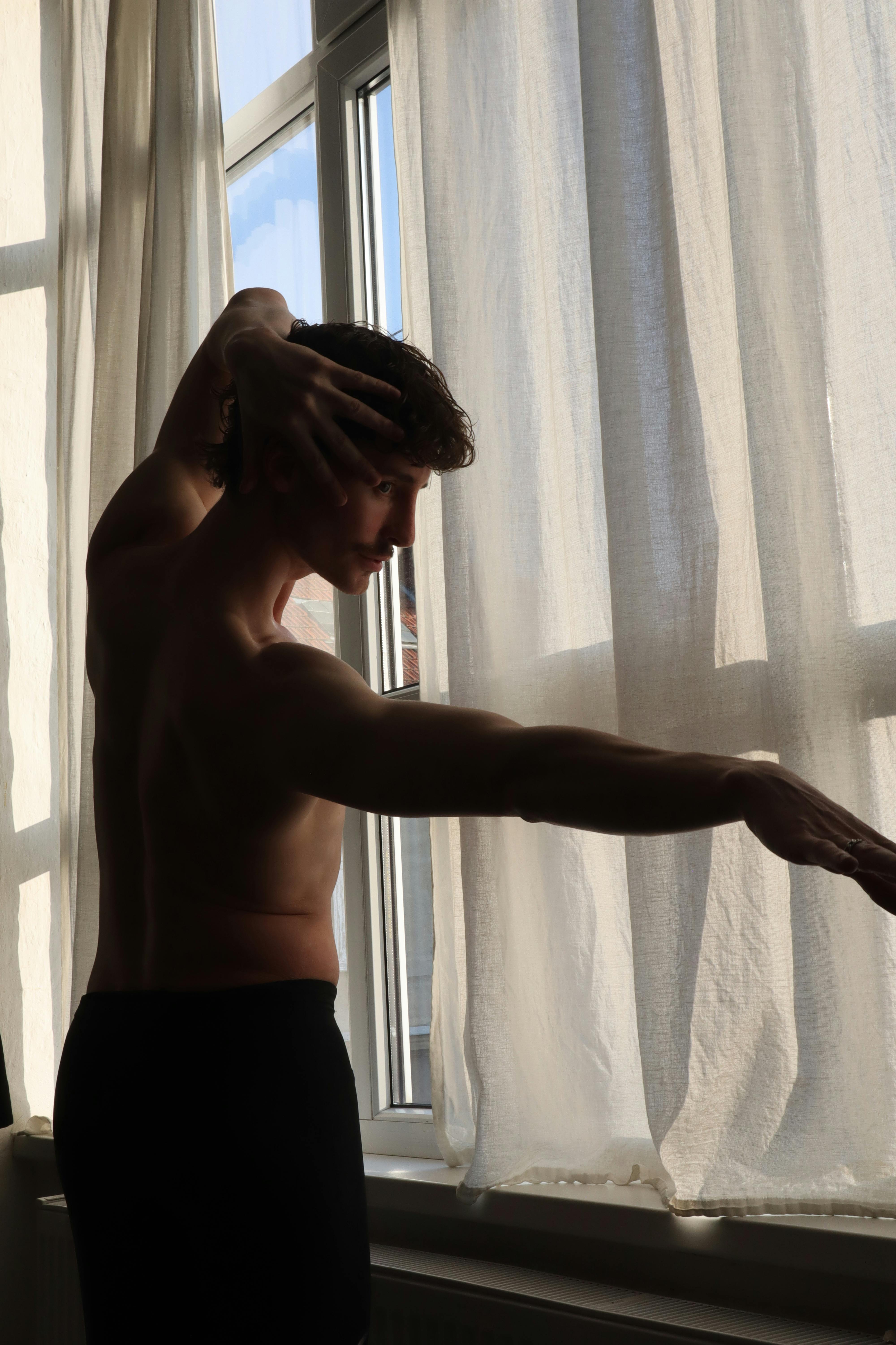 Gratis Silhouette artistica di un ballerino che si esibisce in un interno, vicino a una finestra, a Berlino, trasmettendo grazia e portamento. Foto a disposizione