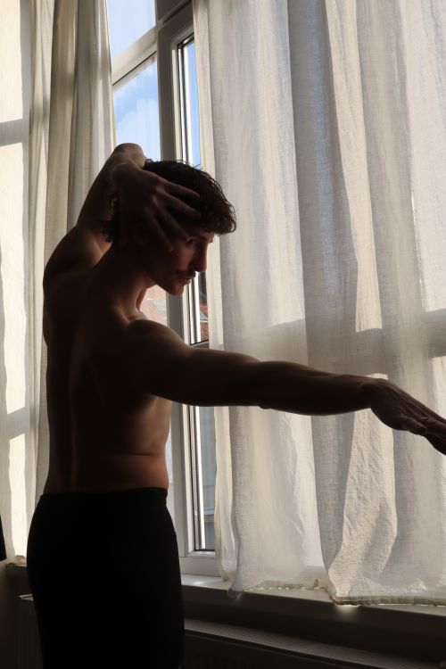 Free Artistic silhouette of a male dancer performing indoors by a window in Berlin, conveying grace and poise. Stock Photo
