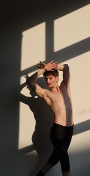 Silhouetted young male dancer in Berlin performing under dramatic shadows.