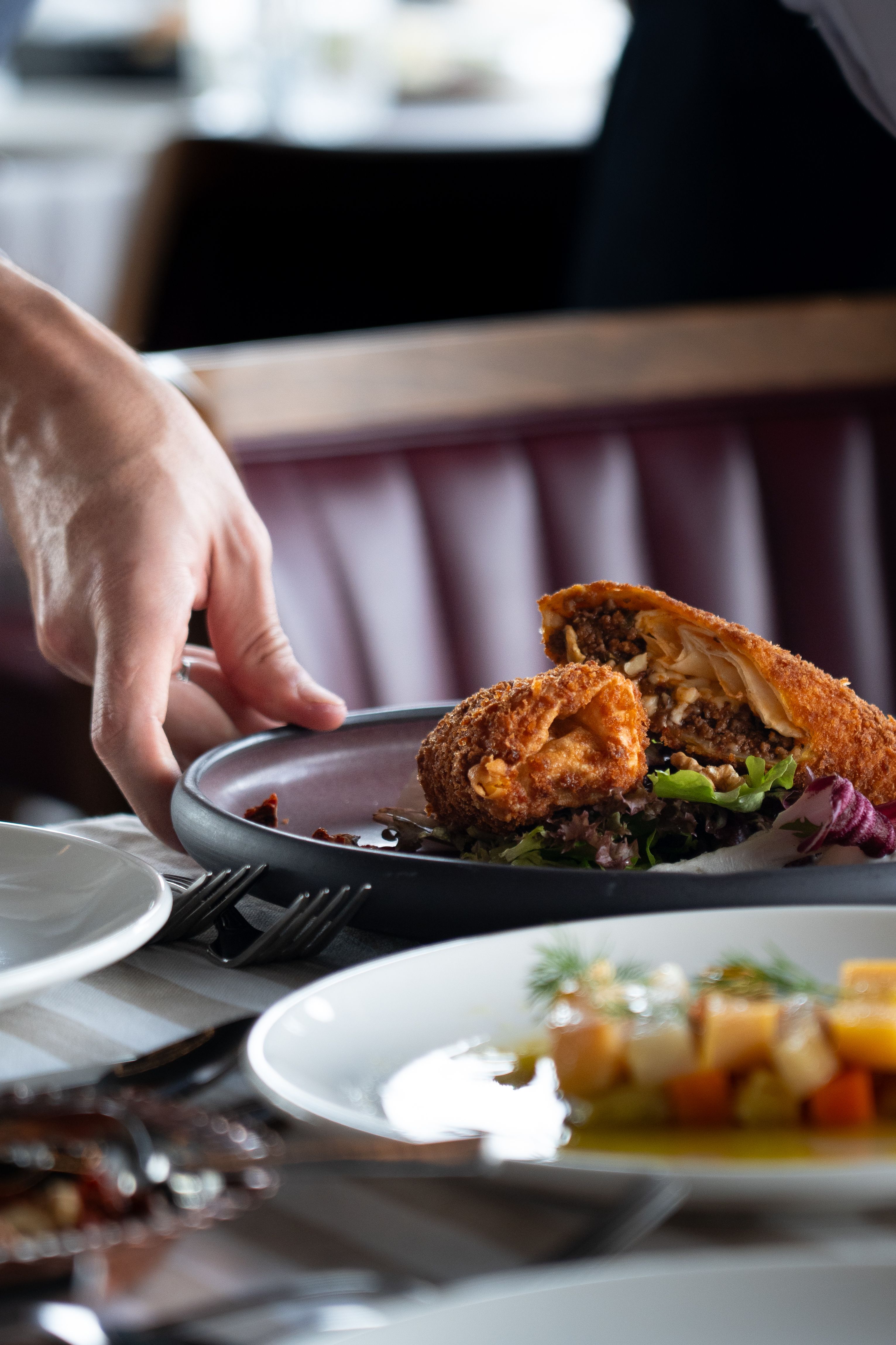 Close-up of a crispy stuffed roll served in a dining setting.