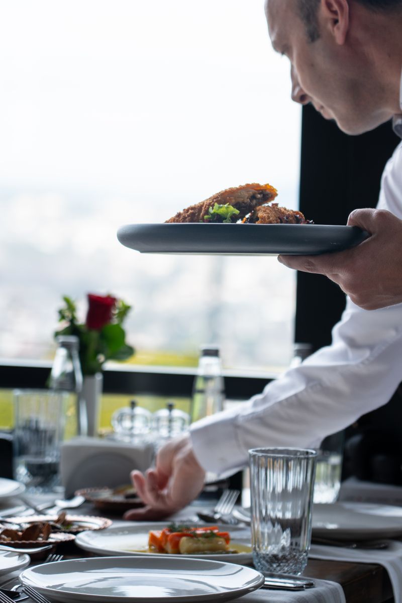 Ospătar profesionist servind un preparat gourmet