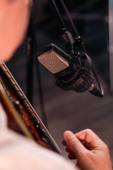 Musician recording acoustic guitar with a professional microphone.