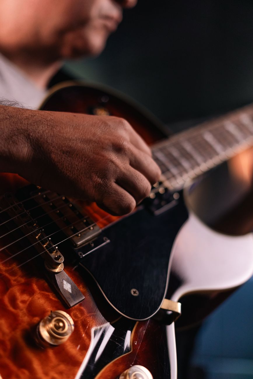 A musician strumming an electric guitar during a live performance.. musician, strumming, electric