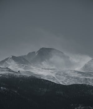 Serene view of snow-covered Rocky Mountains with mist in a calm winter setting.