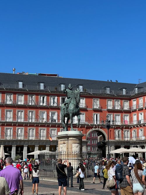 Free Crowded Plaza Mayor in Madrid showcasing historic architecture and equestrian statue under blue sky. Stock Photo