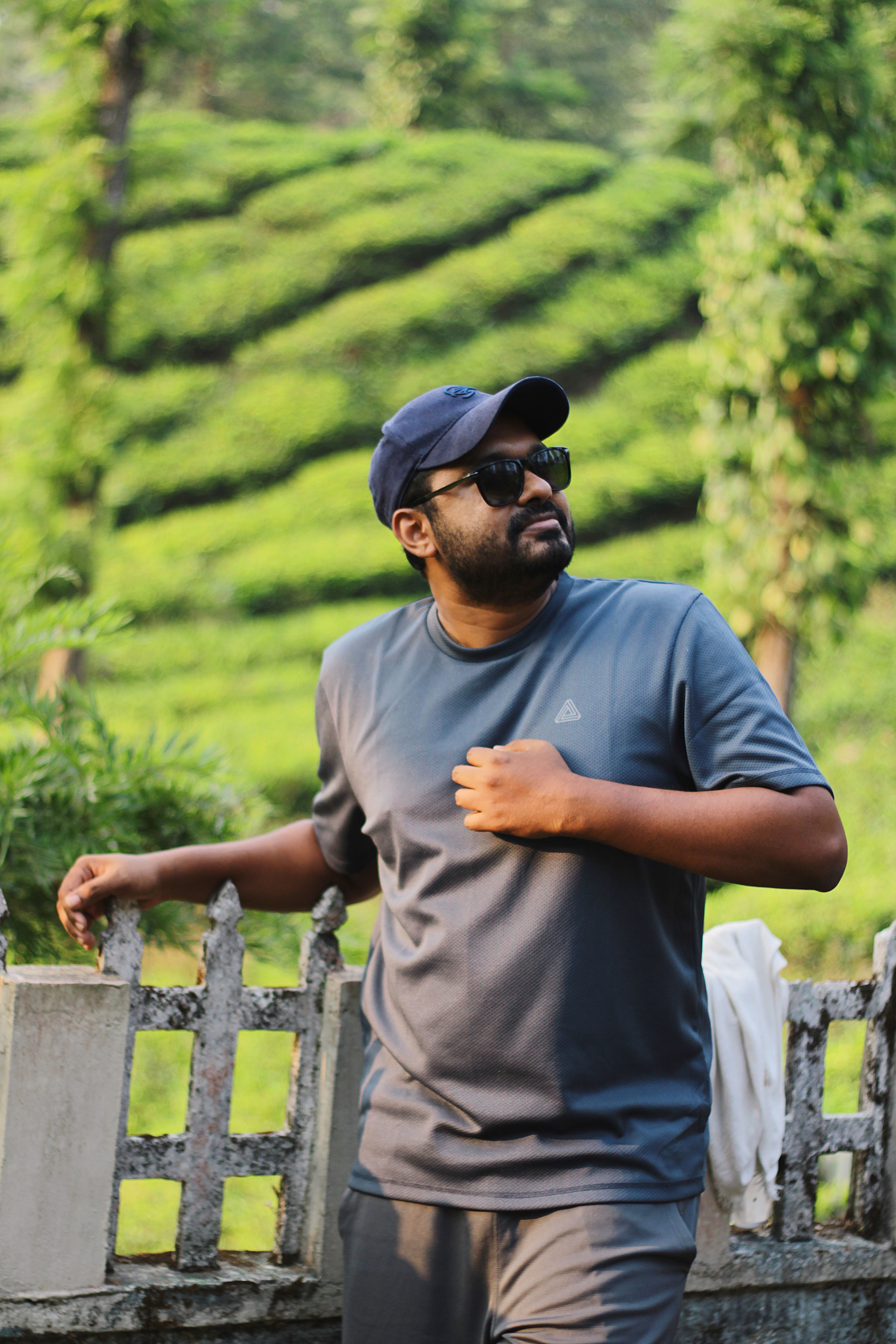 Man stands casually in verdant tea plantation, showcasing tropical serenity.