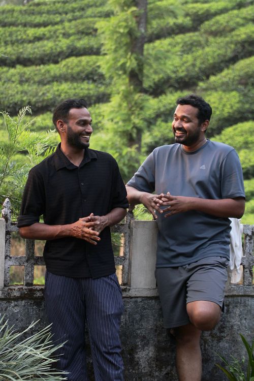 Free Two men enjoying a conversation in a lush tea plantation. Stock Photo