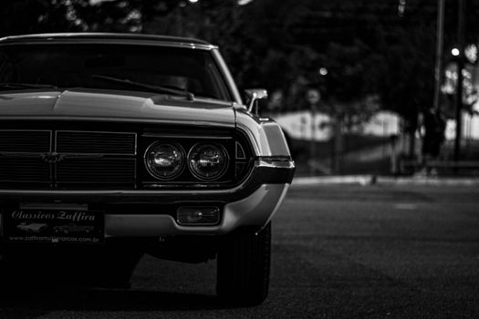 Black and white photo of a vintage car front, capturing classic automotive details at night.