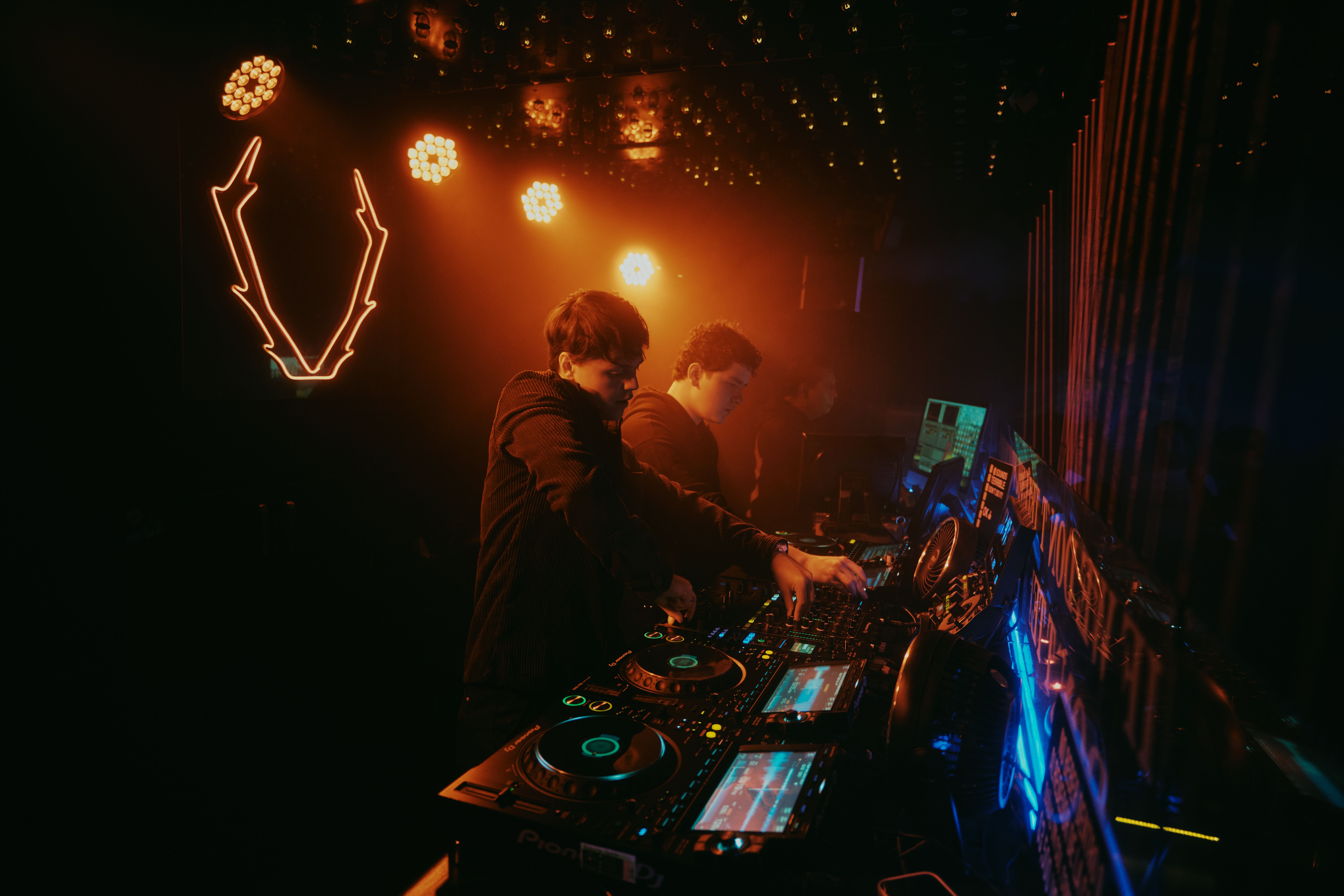 DJs energize the crowd under vibrant neon lights at a bustling nightclub in Leon, Mexico.