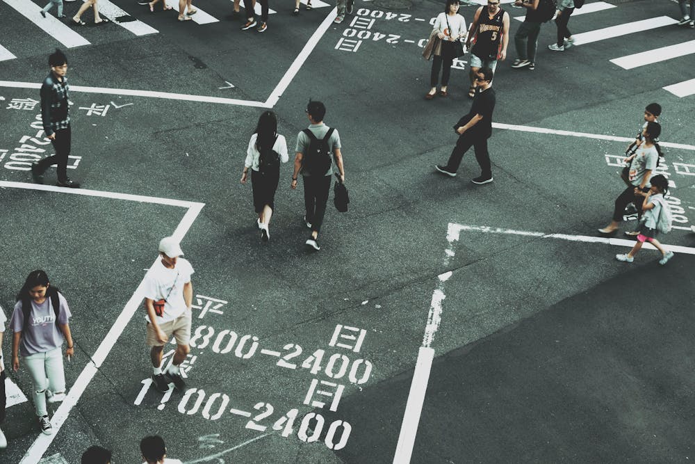 Pedestrians walking along a road. | Photo: Pexels