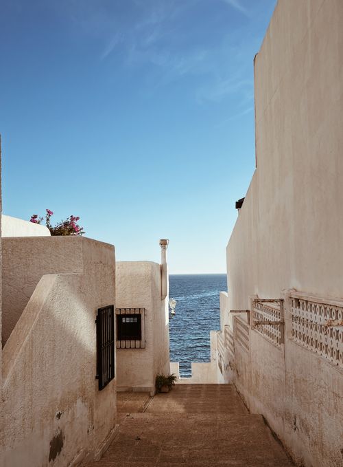 Free Picturesque whitewashed alleyway with ocean view on a sunny day. Stock Photo