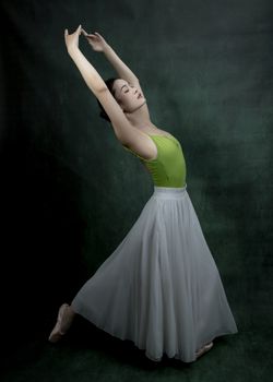 A ballerina performs a graceful pose in a studio, showcasing elegance and poise in her dance.