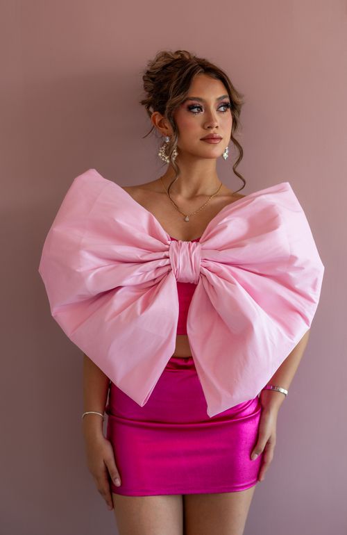 Free Stylish woman in pink outfit featuring a large bow, posing indoors. Stock Photo