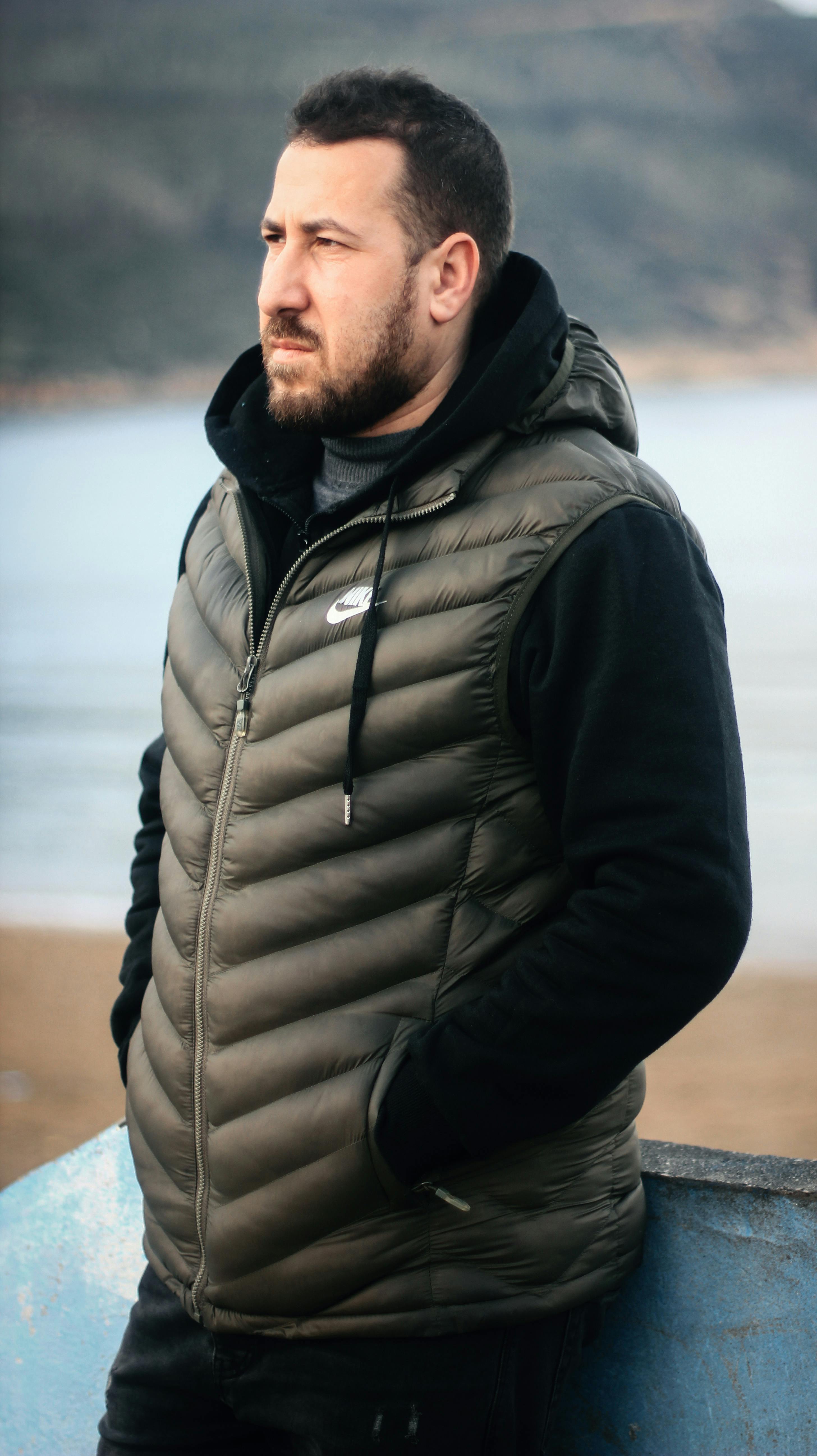 A man in a jacket standing on a beach in Collo, Algeria, looking thoughtful.