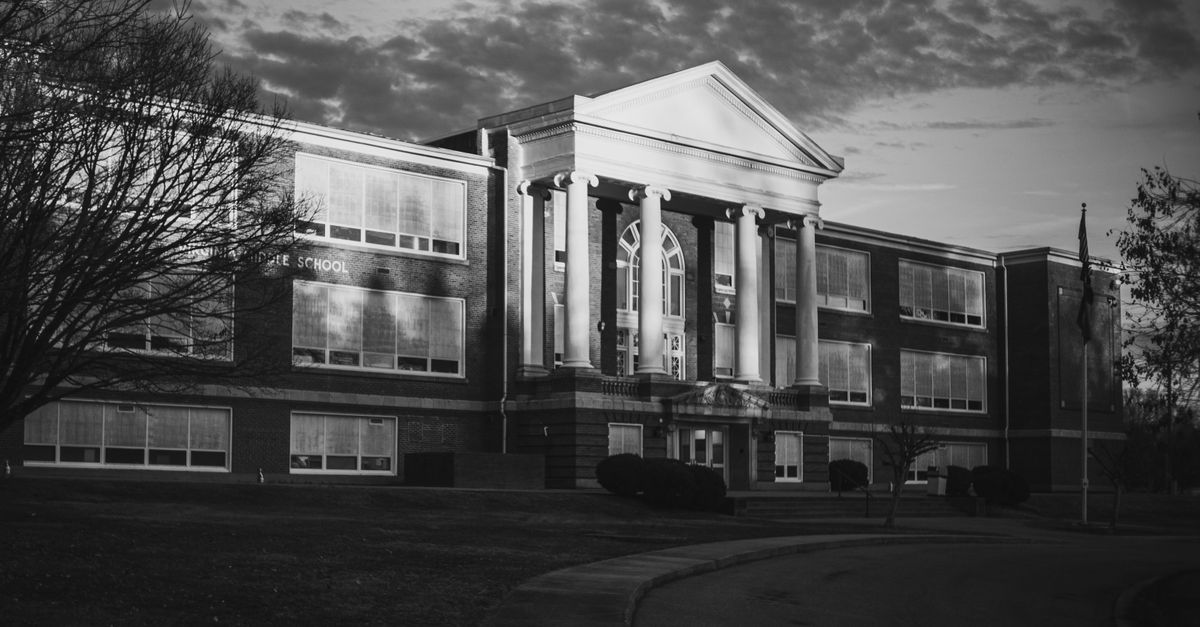 Classic black and white photo of a historic school building with dramatic lighting at dusk.