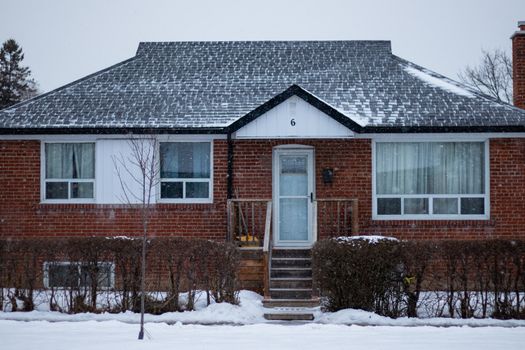 A suburban brick house in Toronto covered with snow on a winter day.