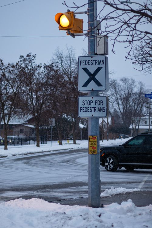 Free Pedestrian crossing sign in snowy Toronto street during winter twilight. Stock Photo
