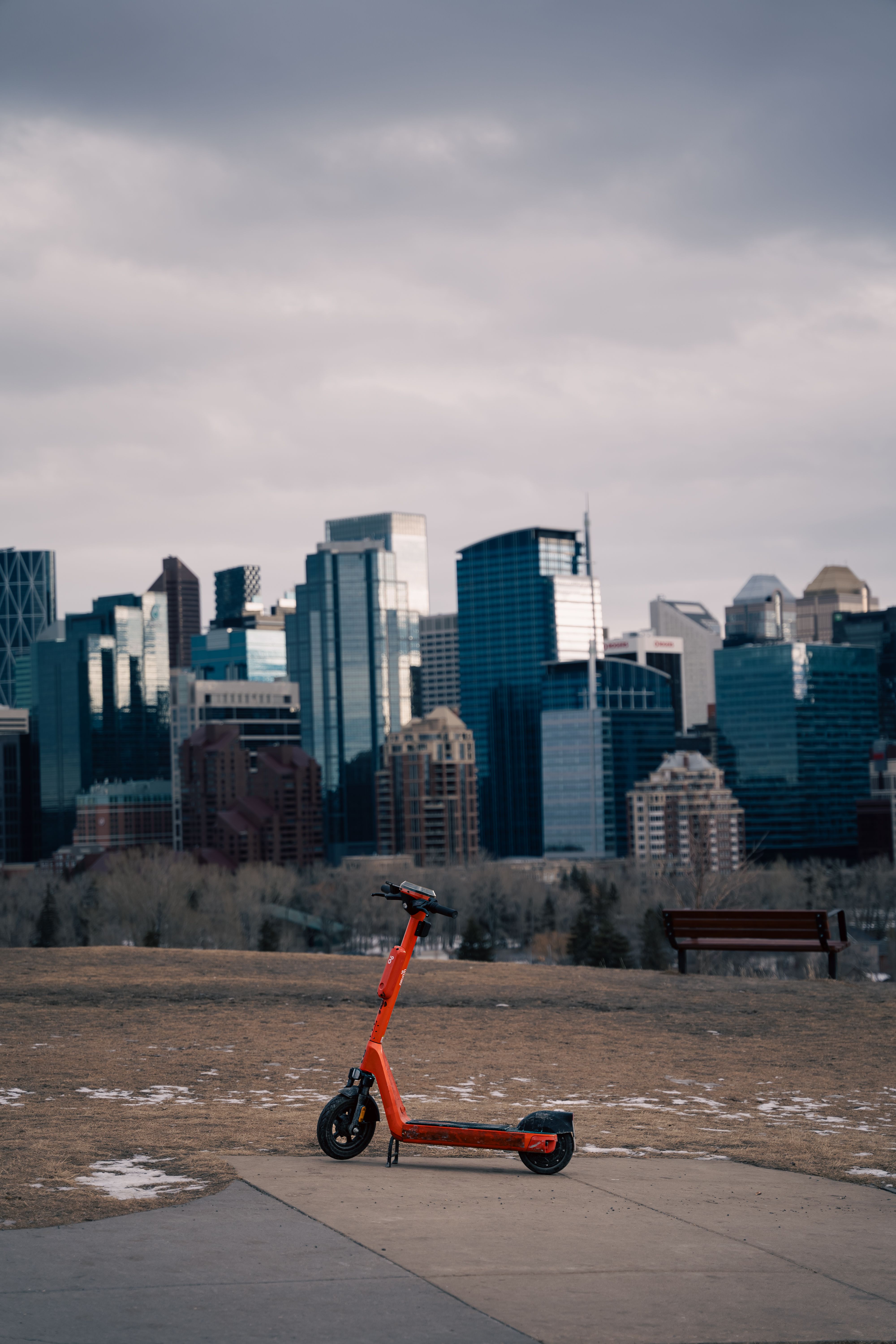 Orange Electric Scooter in Calgary Skyline View · Free Stock Photo