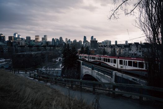 Scenic view of Calgary skyline with train crossing bridge at twilight. Urban cityscape with transportation.