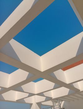 Modern white geometric structure with clear blue sky creating an abstract view.