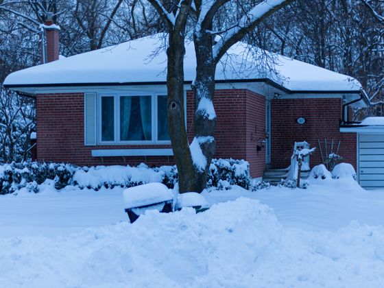 A house and garden buried under deep snow on a winter morning