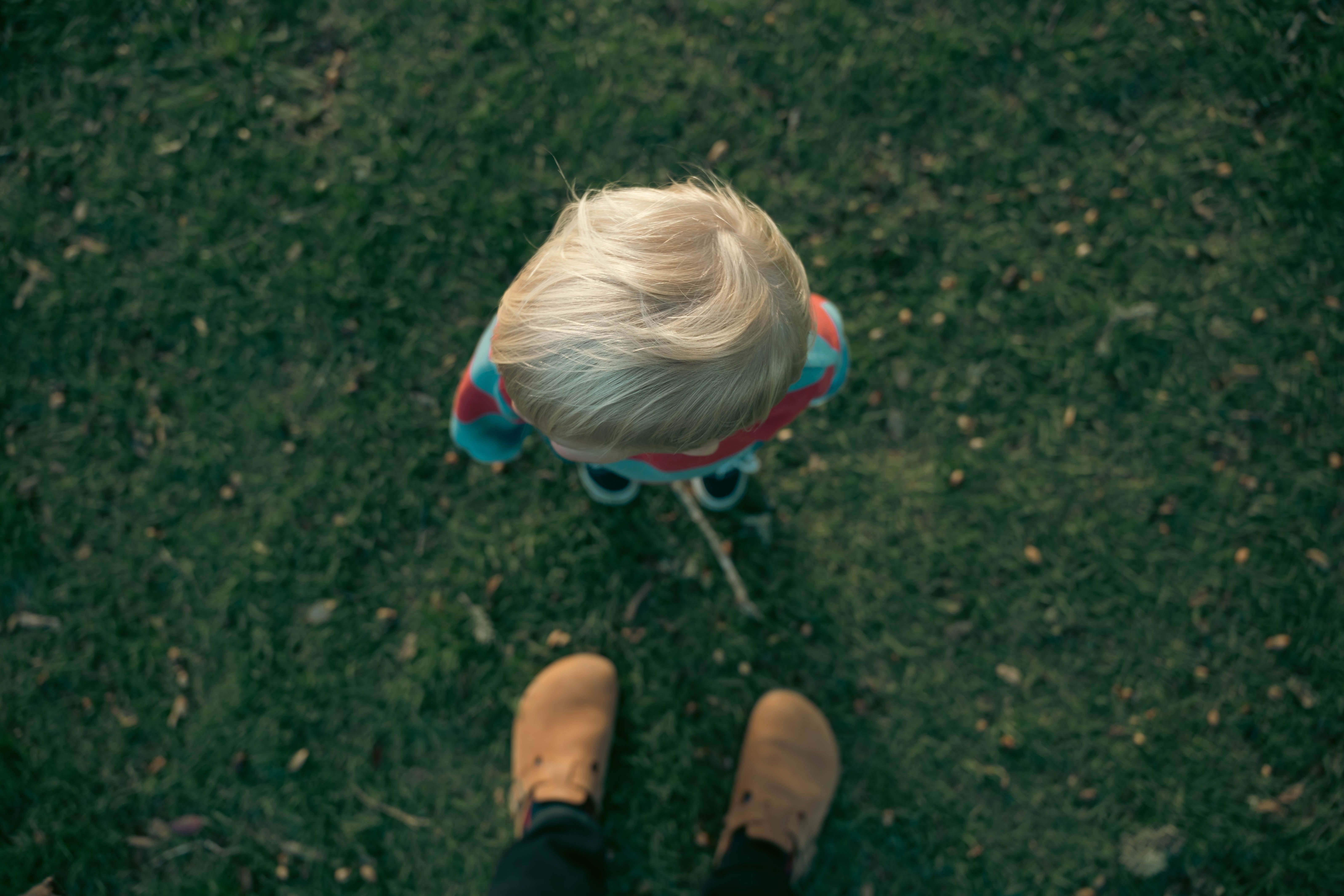 Bird's-eye view of a child on grass, showcasing perspective and outdoor play.