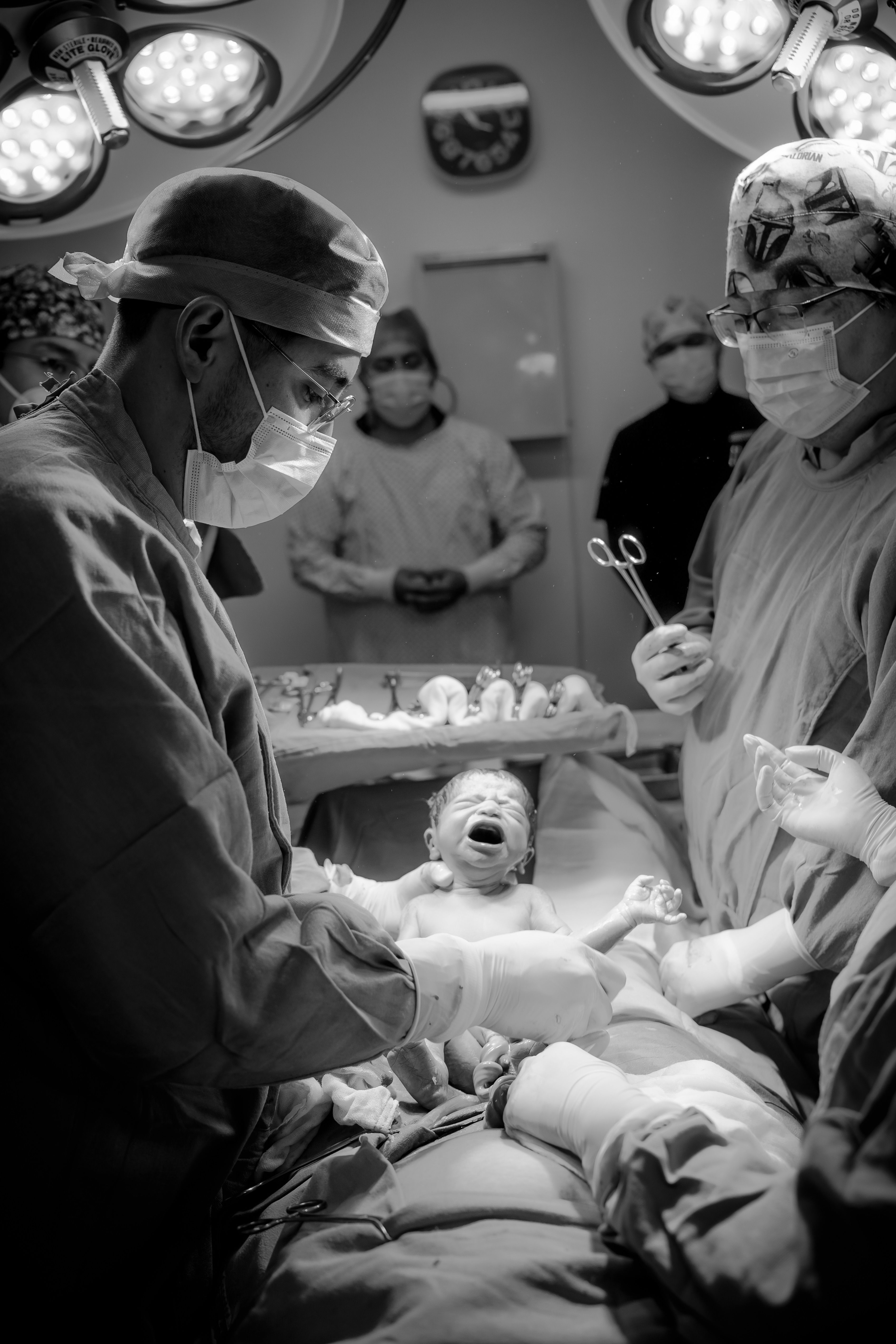 Doctors and medical staff delivering a newborn in a hospital operating room.