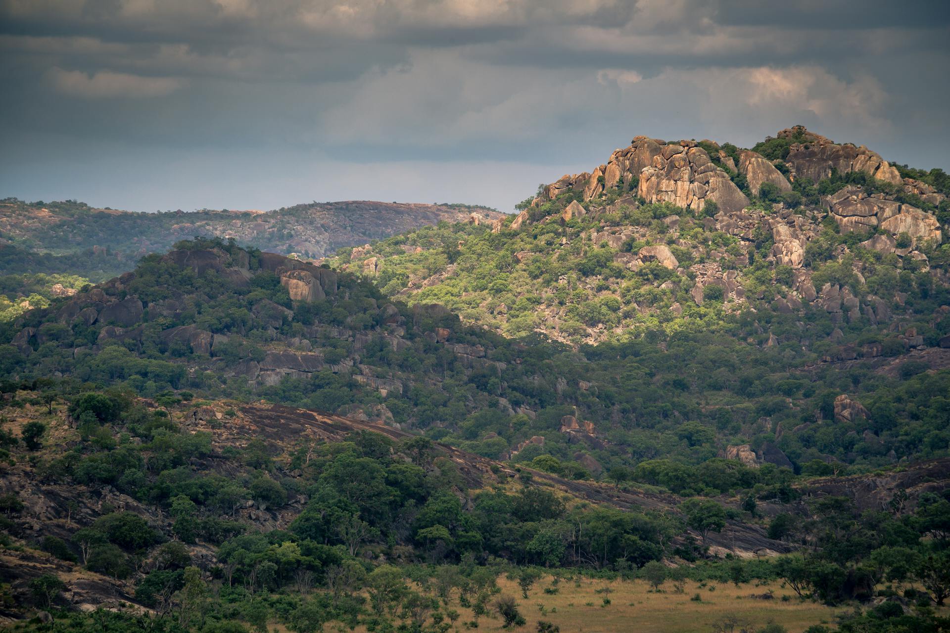 Aerial view of lush, rocky hills in Zimbabwe under a cloudy sky, showcasing natural beauty.