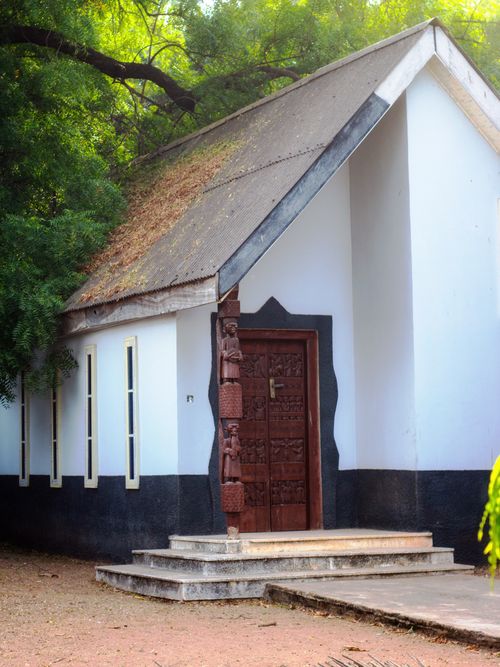 Free Rustic African church with wooden carved door and sloped roof captured in summer setting. Stock Photo
