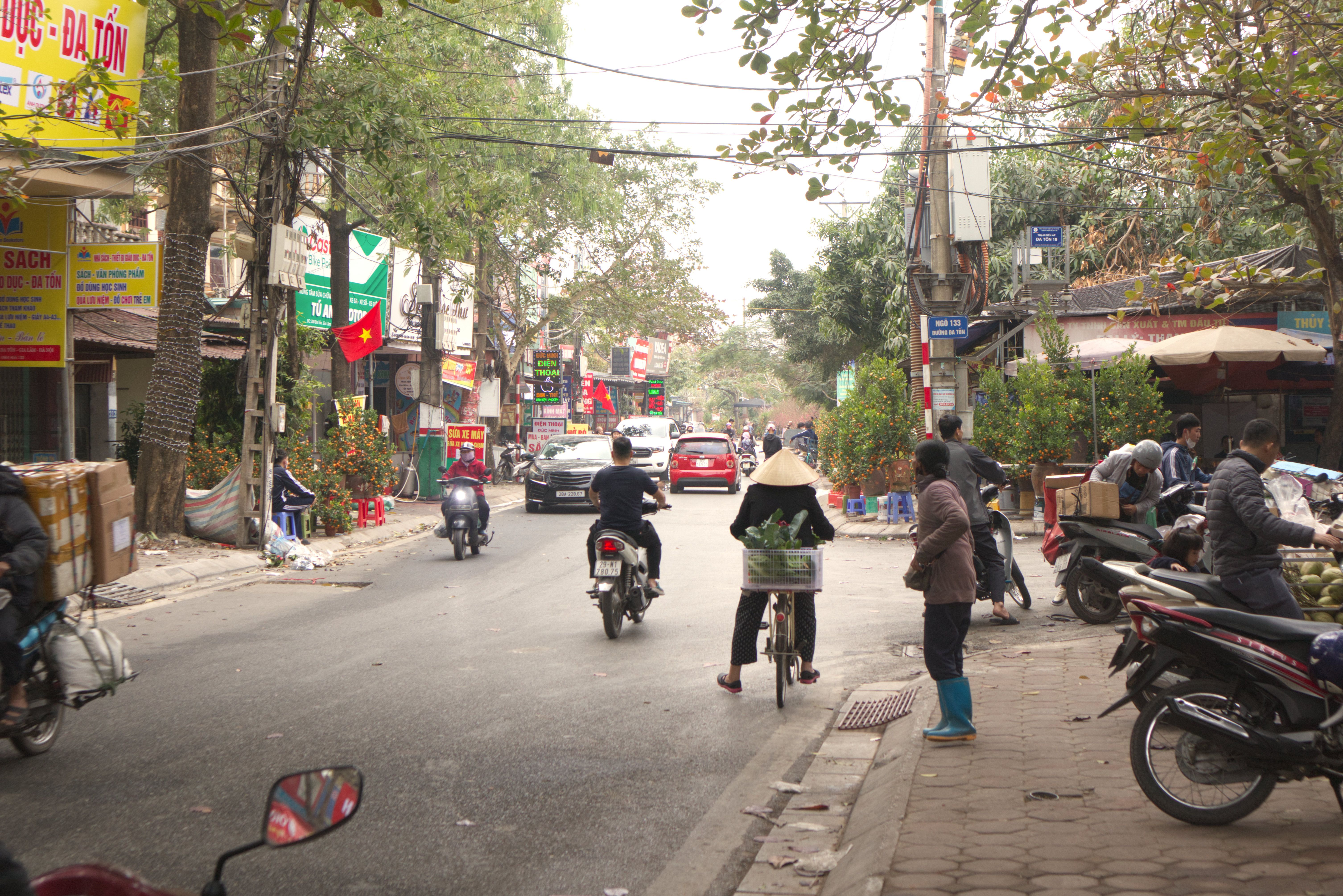 bustling street market scene in Hanoi with a visible cell tower in the background, illustrating connectivity amid traditional life