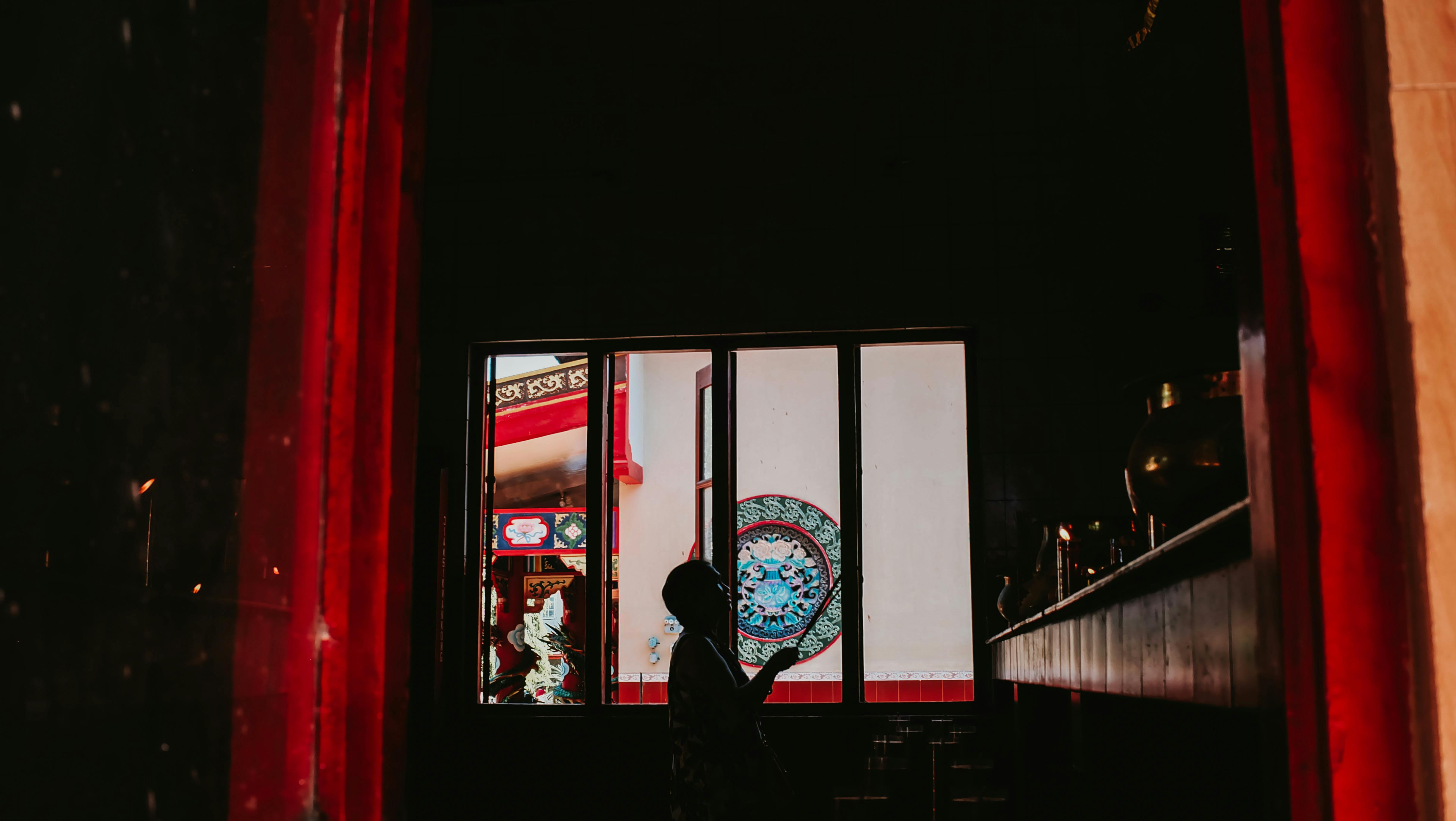 Gratis Silhuett av en person med røkelse i en tradisjonell kinesisk bygning i Indonesia. Arkivbilde