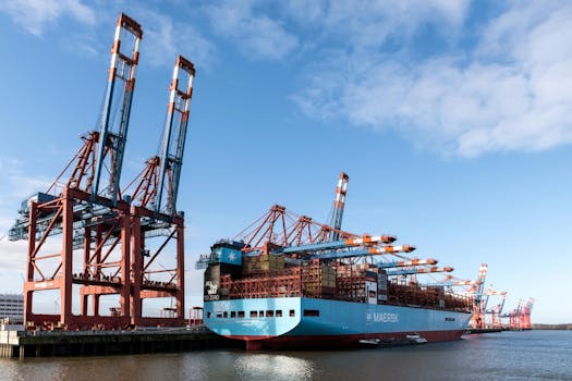 A large container ship is docked at Hamburg port, surrounded by cranes and shipping containers.