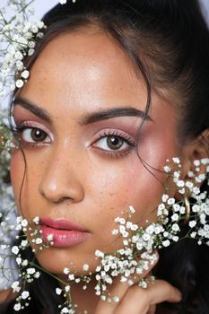 Close-up portrait of an elegant bride surrounded by delicate white flowers.