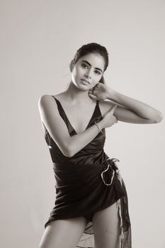 Monochrome portrait of a woman in fashionable black dress, striking an elegant pose.