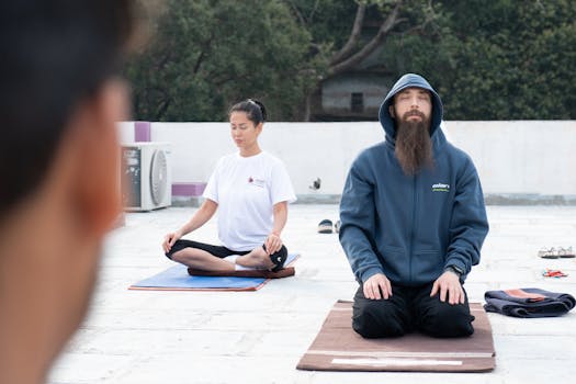 People practicing outdoor yoga meditation on a rooftop in Rishikesh, India.
