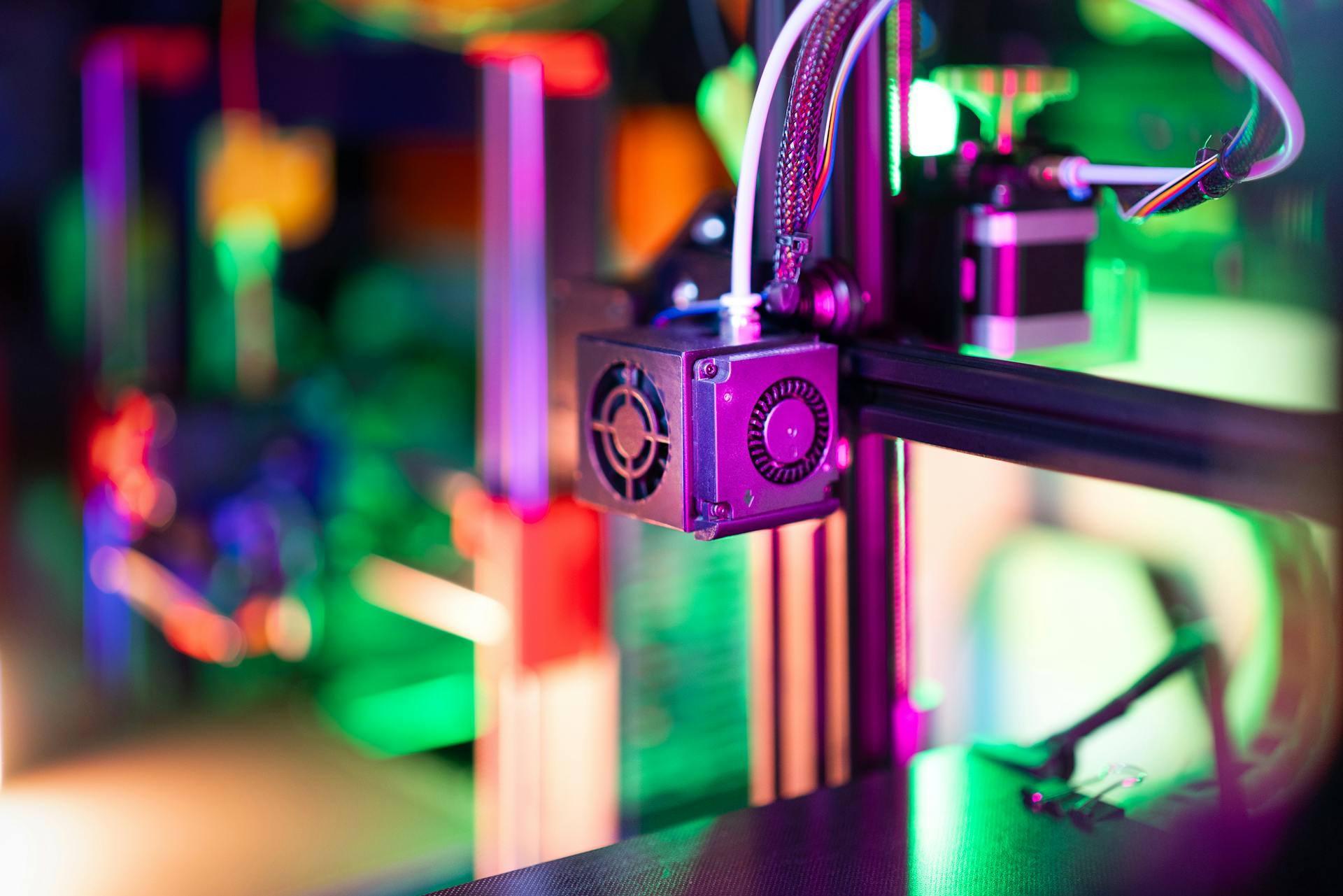 Vibrant neon-lit 3D printer in a modern workshop setting, showcasing advanced technology.