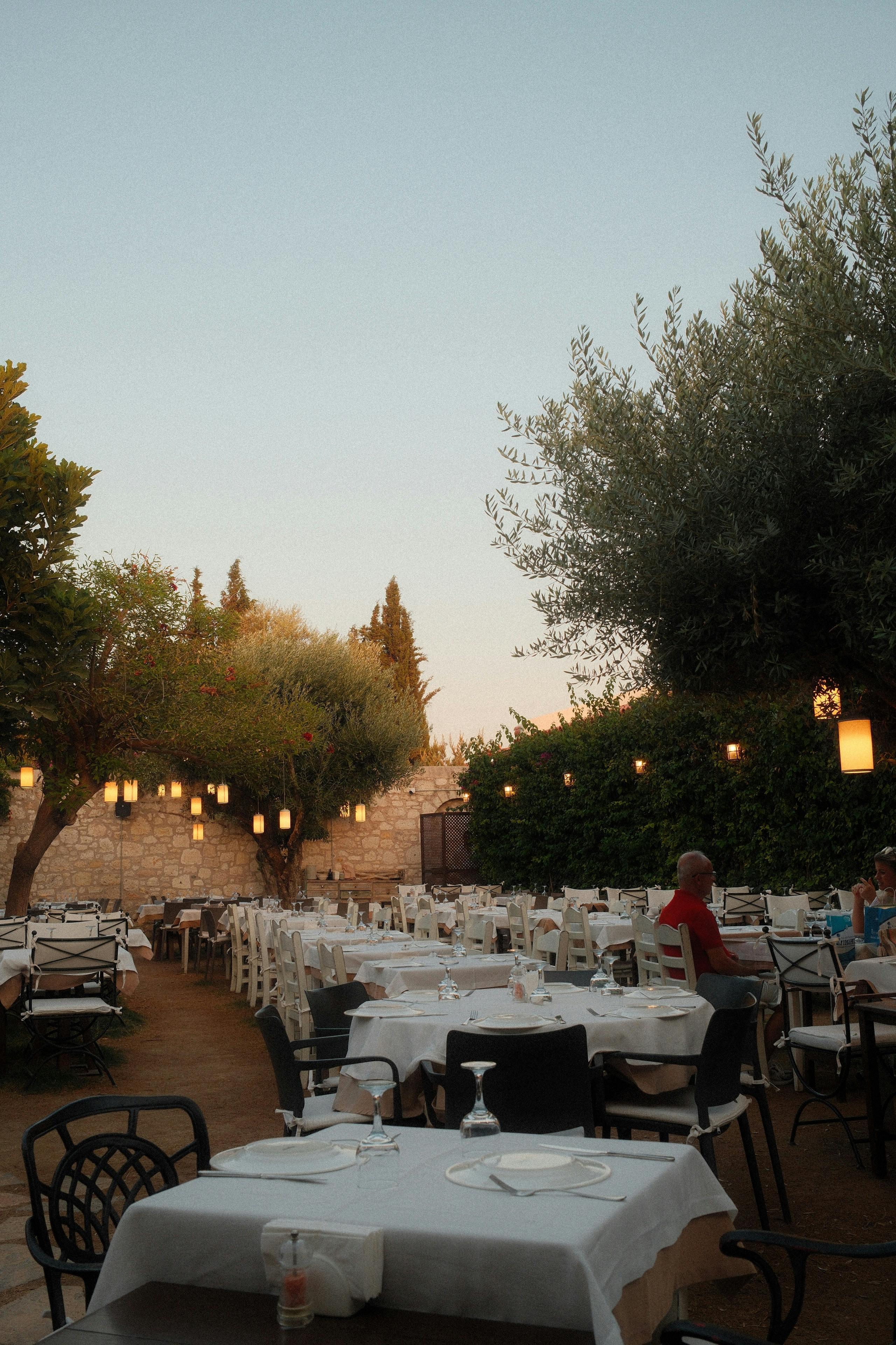 De franc Un acollidor restaurant a l'aire lliure amb taules i fanals durant el crepuscle. Foto d'estoc
