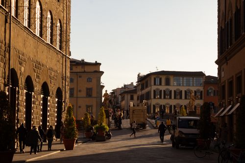 Free A lively street in Florence with historic buildings and sculptures at dusk, capturing the essence of Italian architecture. Stock Photo