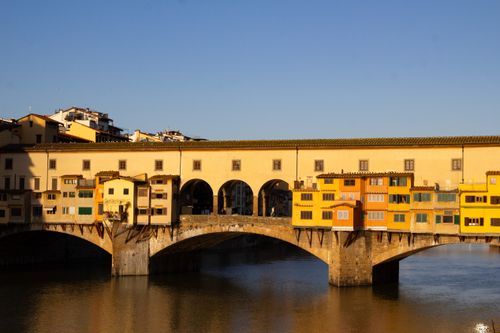 Free Ponte Vecchio bridge with vibrant buildings over Arno River in Florence during day. Stock Photo