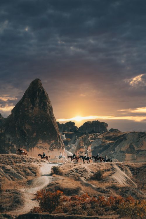 Free A scenic view of horseback riders in Cappadocia's unique landscape during sunset. Stock Photo